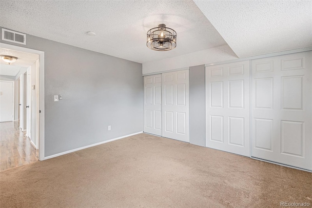 unfurnished bedroom with visible vents, a textured ceiling, baseboards, and carpet floors