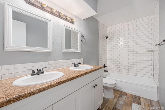 bathroom with toilet, wood finished floors, shower / bathtub combination, and a sink