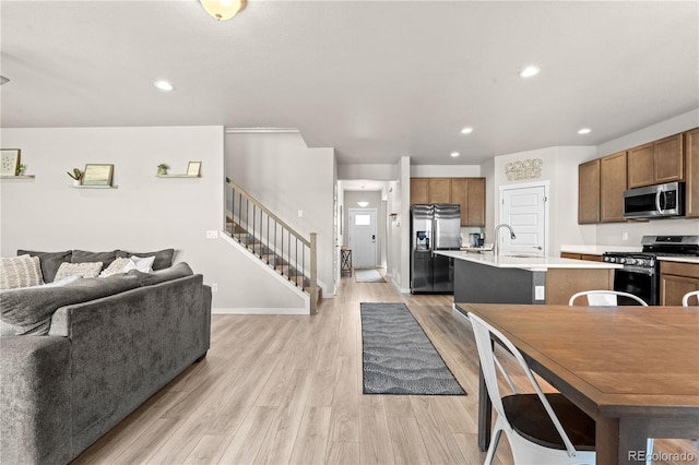 244 Chipeta Way, Lochbuie, CO 80603 - kitchen with stainless steel appliances, open floor plan, a kitchen island with sink, light countertops, and light wood-style floors