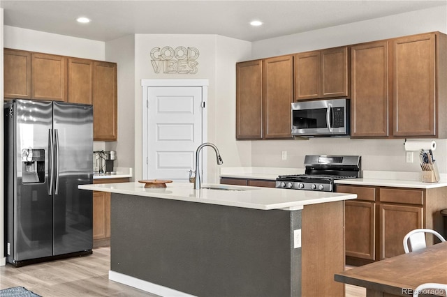 244 Chipeta Way, Lochbuie, CO 80603 - kitchen with appliances with stainless steel finishes, light wood-style flooring, a kitchen island with sink, light countertops, and recessed lighting