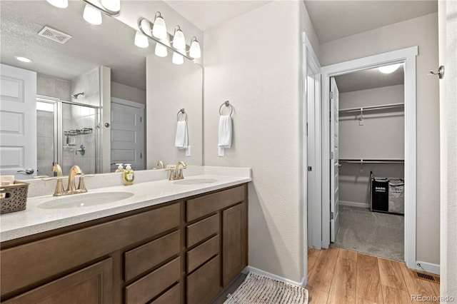 244 Chipeta Way, Lochbuie, CO 80603 - full bath featuring a stall shower, double vanity, a spacious closet, and wood finished floors