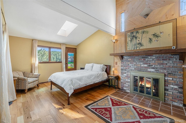 bedroom featuring vaulted ceiling with skylight, a fireplace, and wood finished floors