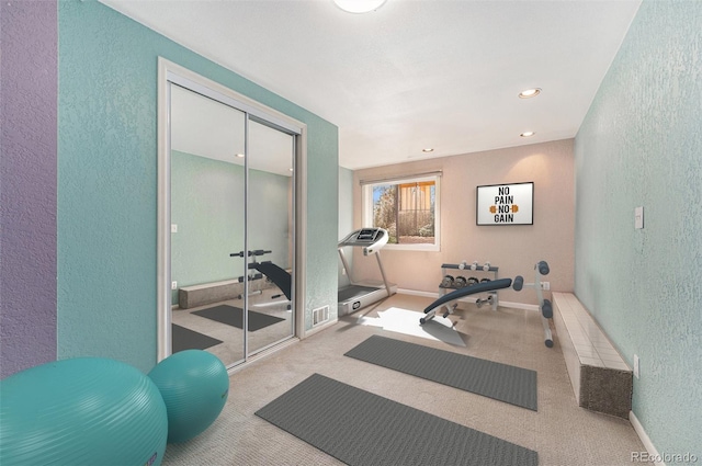 exercise area with a textured wall, recessed lighting, carpet floors, visible vents, and baseboards