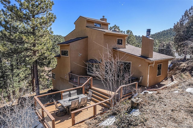 back of house with a chimney, outdoor dining area, and a deck