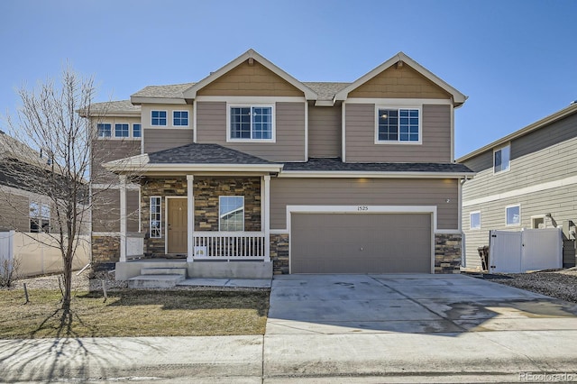 craftsman house featuring covered porch, fence, a garage, stone siding, and driveway