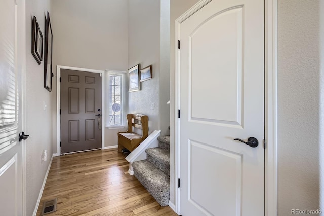 foyer with light wood-style flooring, visible vents, and baseboards