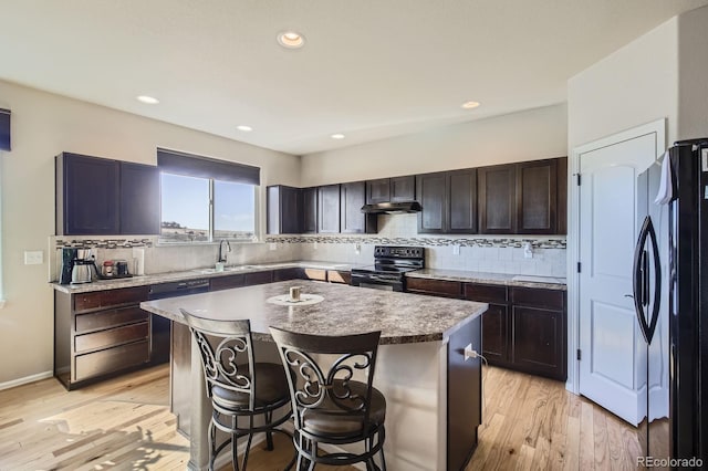 kitchen with black range with electric cooktop, light wood-style flooring, a sink, freestanding refrigerator, and tasteful backsplash