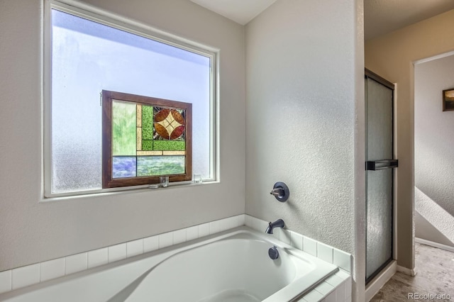 full bathroom featuring a garden tub, a shower stall, and a textured wall