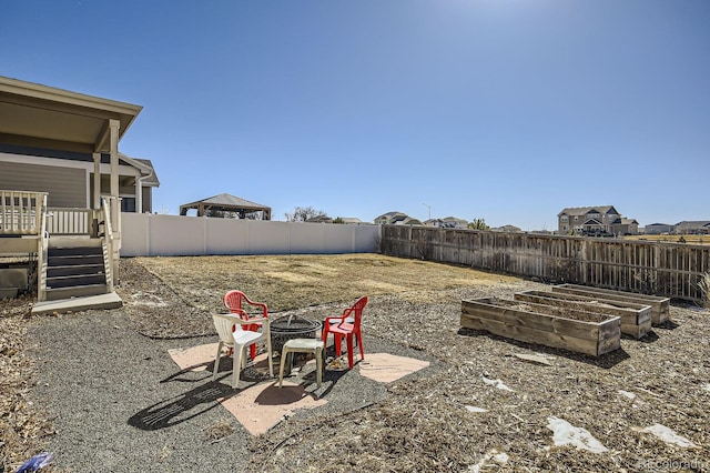 view of yard featuring an outdoor fire pit, a patio area, a fenced backyard, and a vegetable garden