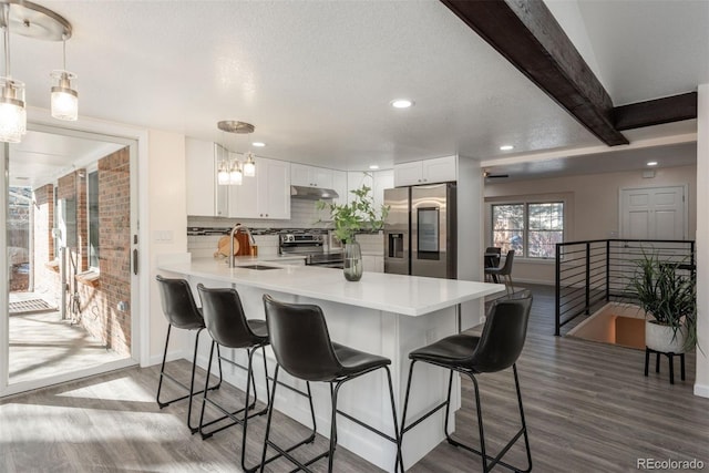 kitchen featuring kitchen peninsula, stainless steel appliances, pendant lighting, and white cabinetry