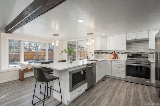 kitchen with decorative light fixtures, white cabinets, a kitchen breakfast bar, and appliances with stainless steel finishes