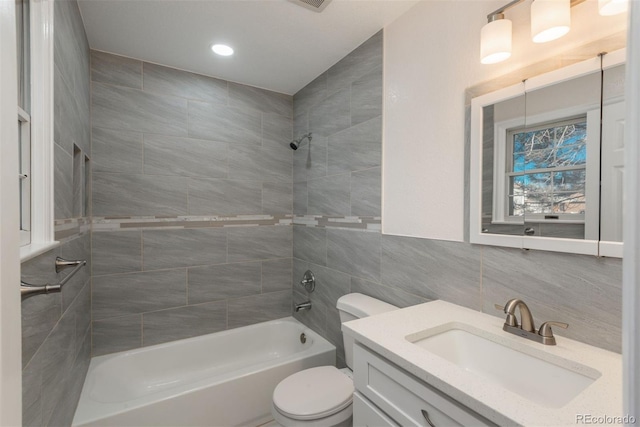 full bathroom featuring toilet, tiled shower / bath, tile walls, vanity, and decorative backsplash