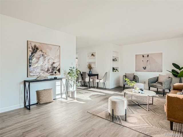 living room with built in shelves and wood-type flooring