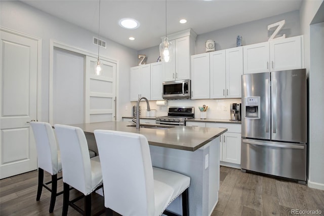 kitchen featuring visible vents, a kitchen island with sink, dark wood-style flooring, white cabinets, and appliances with stainless steel finishes