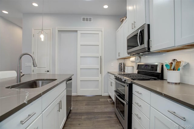 kitchen featuring visible vents, a sink, dark wood finished floors, appliances with stainless steel finishes, and decorative backsplash