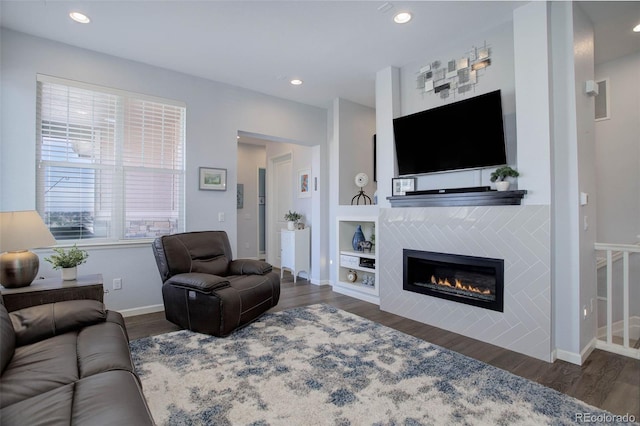 living room with recessed lighting, wood finished floors, baseboards, and a tile fireplace