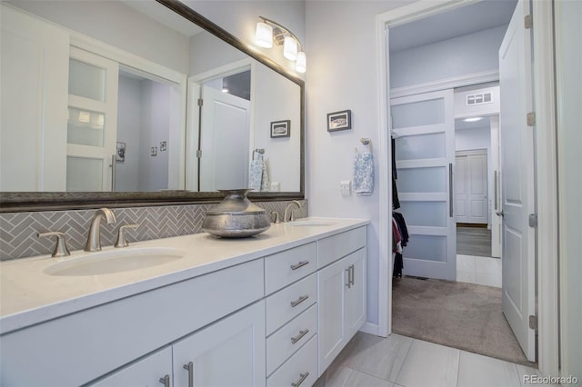 bathroom with double vanity, visible vents, backsplash, and a sink