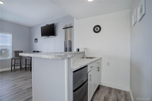 kitchen with baseboards, a peninsula, light countertops, light wood-style floors, and white cabinetry