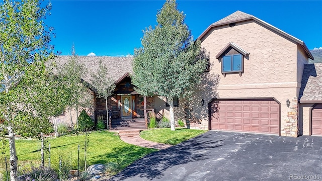 view of front facade with stucco siding, driveway, an attached garage, and a front lawn