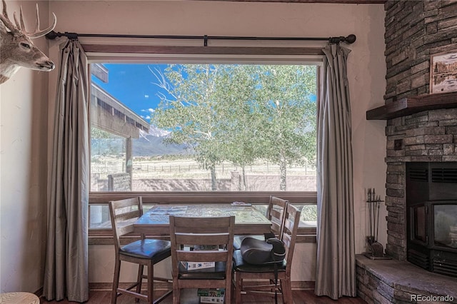 dining room with a stone fireplace, hardwood / wood-style floors, and plenty of natural light