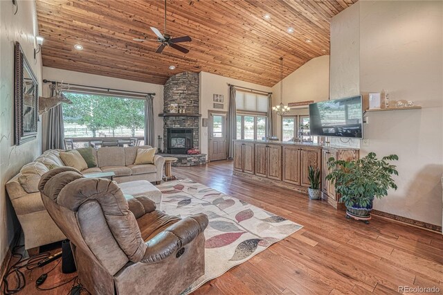 living room featuring light hardwood / wood-style flooring, high vaulted ceiling, plenty of natural light, and a stone fireplace