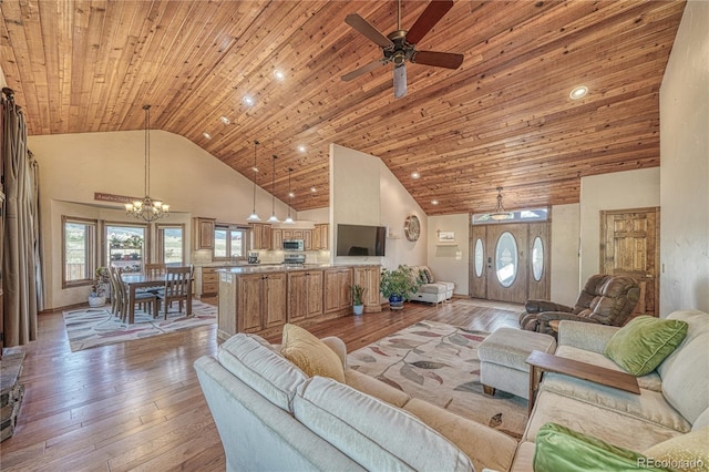 living room featuring light wood-type flooring, ceiling fan with notable chandelier, high vaulted ceiling, and wooden ceiling