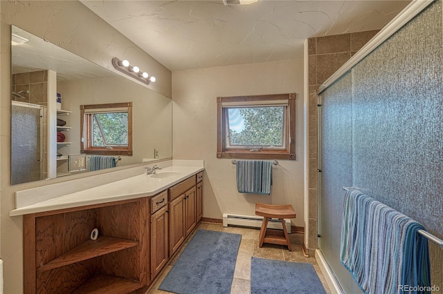 bathroom with vanity, a baseboard radiator, a shower with shower door, and a healthy amount of sunlight