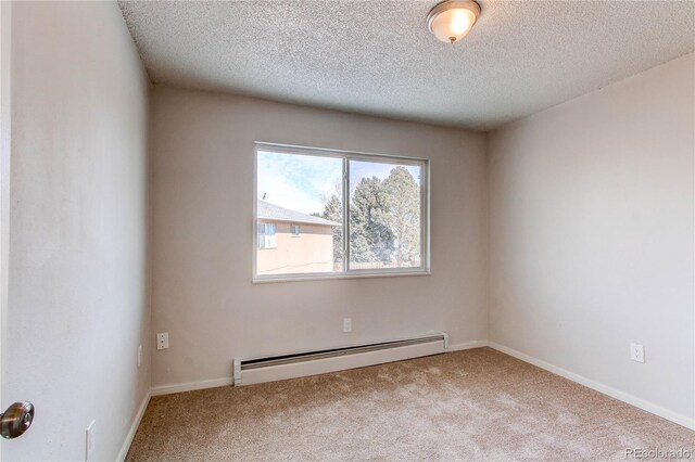 empty room featuring a baseboard heating unit, light carpet, and a textured ceiling