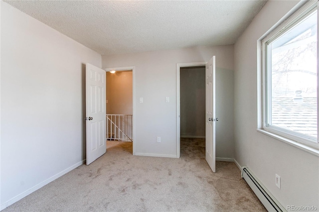 unfurnished bedroom with a baseboard radiator, light carpet, a textured ceiling, and a walk in closet