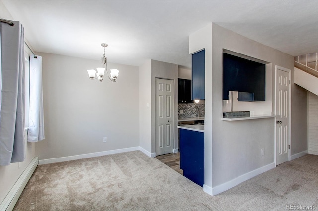 spare room featuring dark carpet, a chandelier, blue cabinets, and baseboard heating