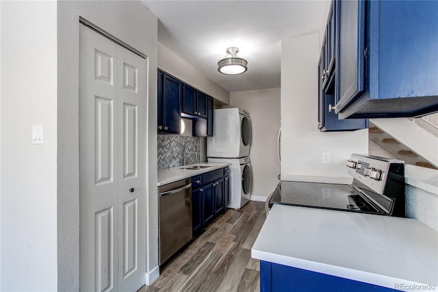 kitchen with appliances with stainless steel finishes, stacked washer and dryer, tasteful backsplash, blue cabinets, and sink