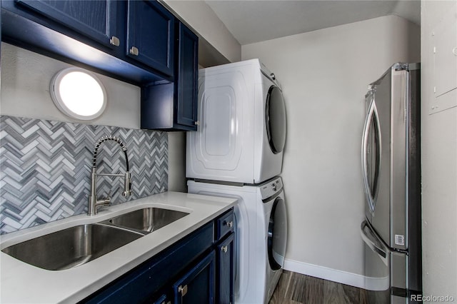 clothes washing area with sink, dark wood-type flooring, and stacked washer / drying machine