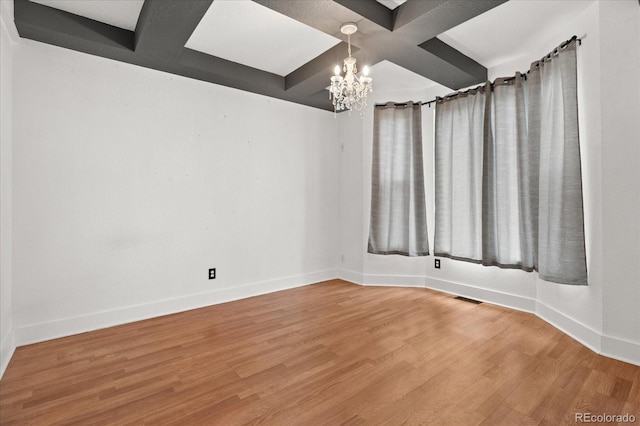 unfurnished room featuring a notable chandelier, visible vents, baseboards, and wood finished floors