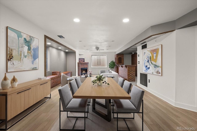 dining space with visible vents, light wood-style flooring, recessed lighting, baseboards, and a brick fireplace