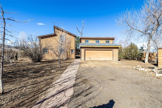 view of front of home with a garage and dirt driveway