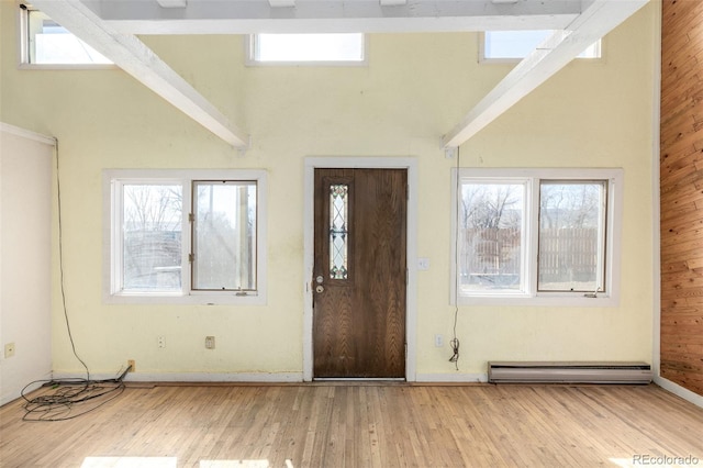 foyer with a high ceiling, baseboard heating, and wood finished floors