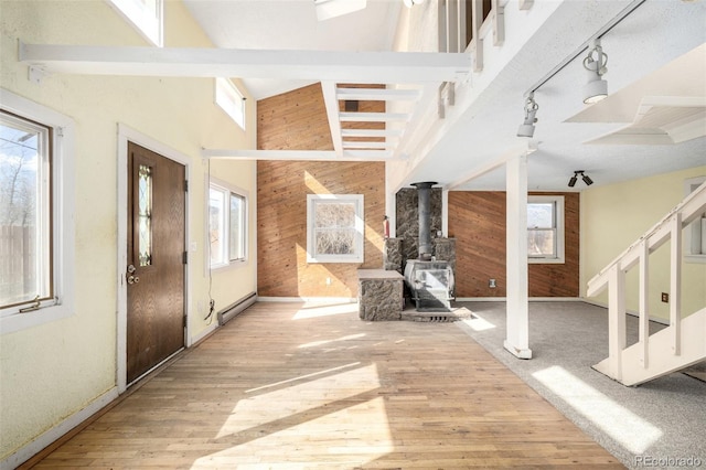 entryway with a wood stove, wooden walls, stairway, and a wealth of natural light