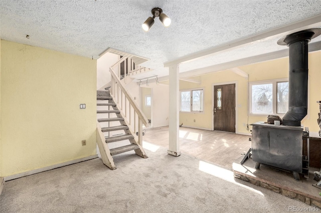 interior space with carpet, a wood stove, plenty of natural light, and stairway