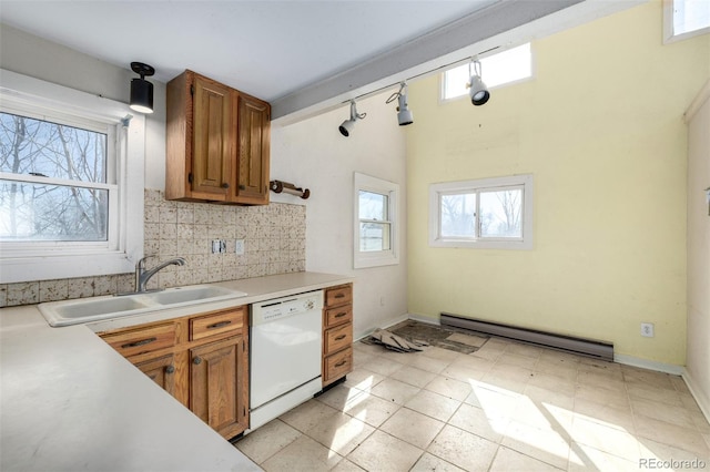 kitchen with tasteful backsplash, light countertops, a baseboard heating unit, white dishwasher, and a sink