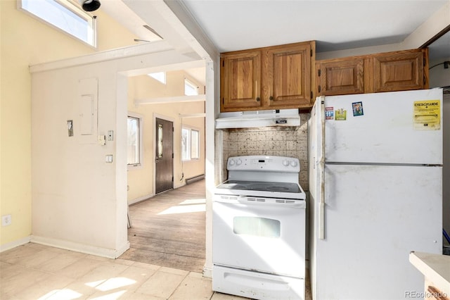 kitchen with brown cabinets, backsplash, a baseboard heating unit, white appliances, and under cabinet range hood