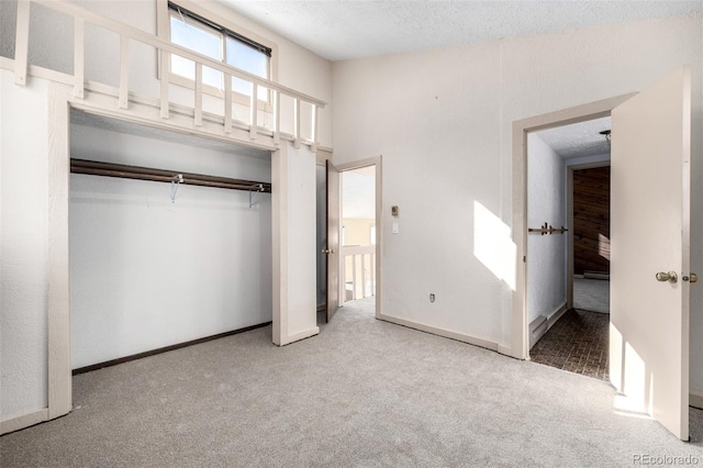 unfurnished bedroom featuring carpet, a closet, a textured ceiling, and baseboards