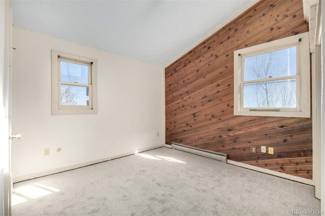 carpeted spare room with lofted ceiling, wood walls, a baseboard radiator, and a wealth of natural light