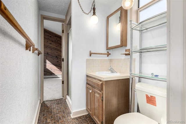 bathroom with toilet, a textured ceiling, vanity, and decorative backsplash