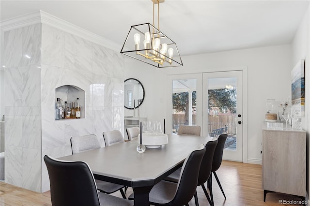 dining area with crown molding, tile walls, and light wood-type flooring