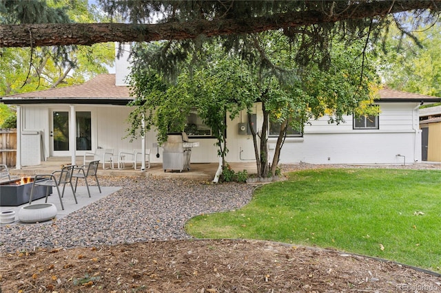 rear view of house featuring a yard, a patio area, and an outdoor fire pit