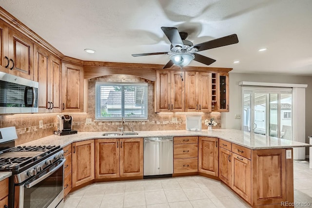 kitchen with light stone countertops, sink, stainless steel appliances, tasteful backsplash, and kitchen peninsula