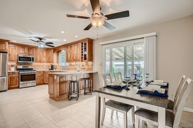 kitchen with stainless steel appliances, tasteful backsplash, kitchen peninsula, a kitchen bar, and light tile patterned floors