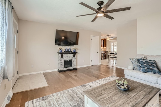 living room featuring ceiling fan, wood-type flooring, and a fireplace