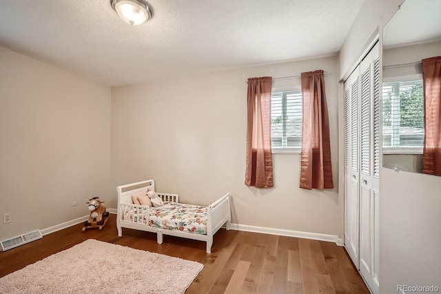 bedroom with hardwood / wood-style flooring, a textured ceiling, and a closet