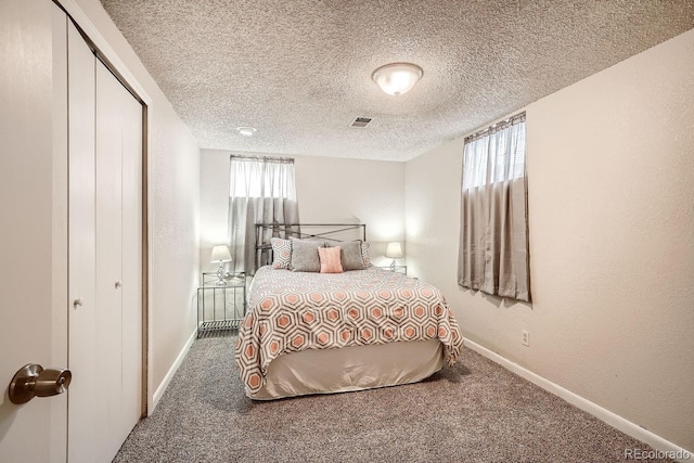 carpeted bedroom with a closet, a textured ceiling, and multiple windows